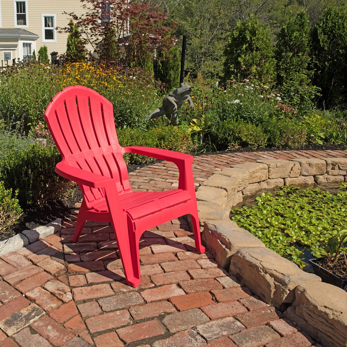 A red Adirondack chair on a stone pathway.