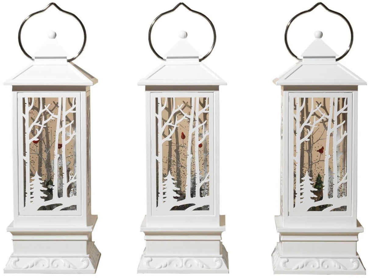 White lantern decoration with glitter and a woodland scene with a cardinal inside.