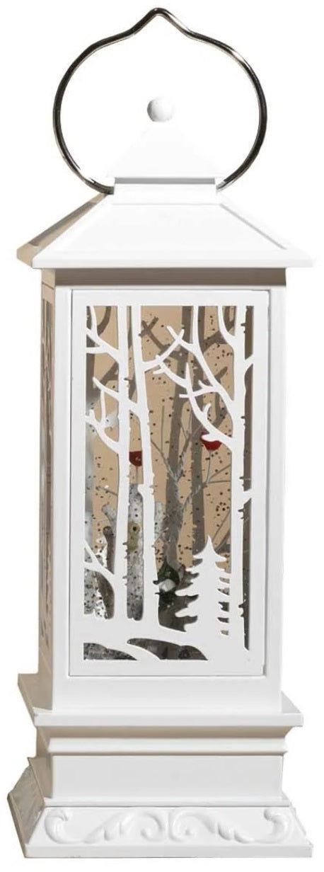White lantern decoration with glitter and a woodland scene with a cardinal inside.