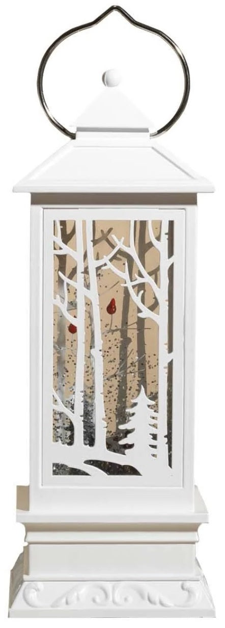 White lantern decoration with glitter and a woodland scene with a cardinal inside.