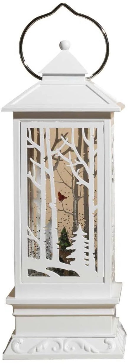 White lantern decoration with glitter and a woodland scene with a cardinal inside.