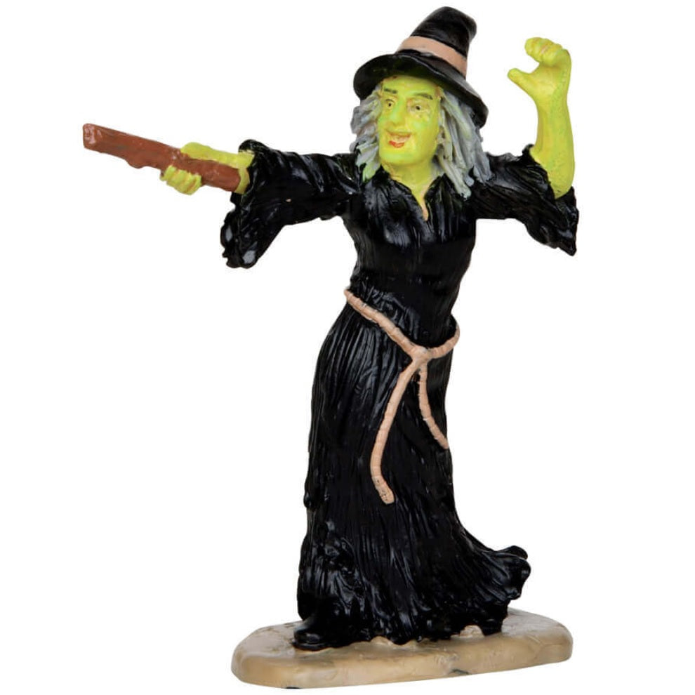 Polyresin figurine for a Lemax display. Designed to look like a witch with green skin. She's wearing a pointy black hat, a black robe and is holding a wand.
