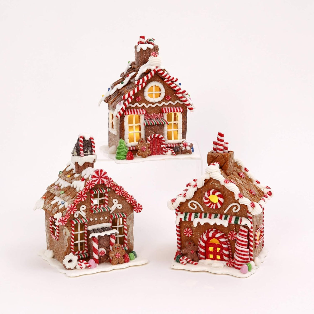 Three tabletop decorations, all designed to look like decorated gingerbread houses. Each one has frosting, peppermint, gummy and sugar accents.