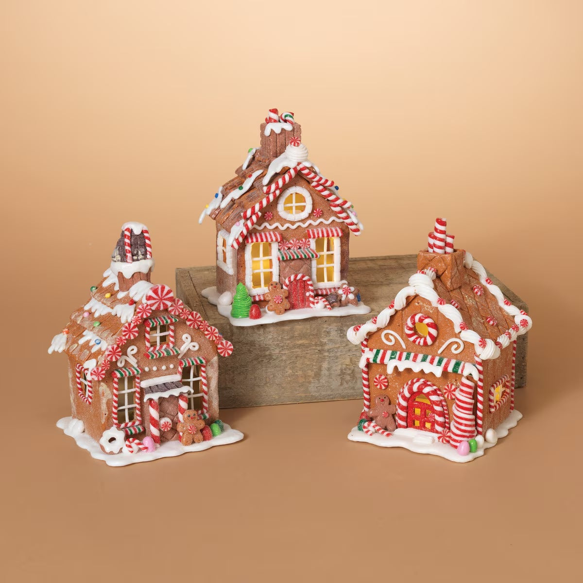 Three tabletop decorations, all designed to look like decorated gingerbread houses. Each one has frosting, peppermint, gummy and sugar accents.