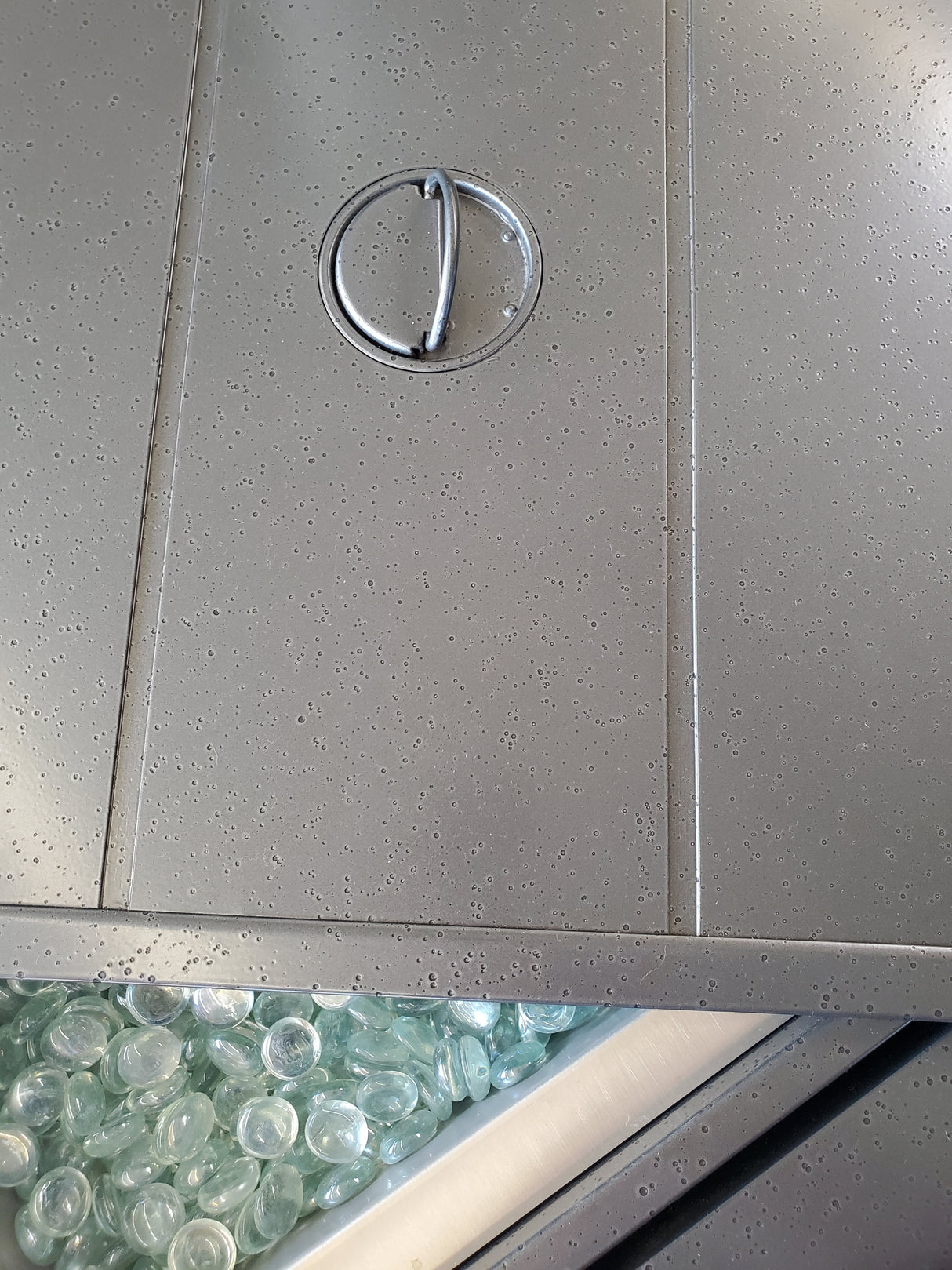 This is an up close view of the lid of this fire pit table. It's partially covering the fire glass inside.