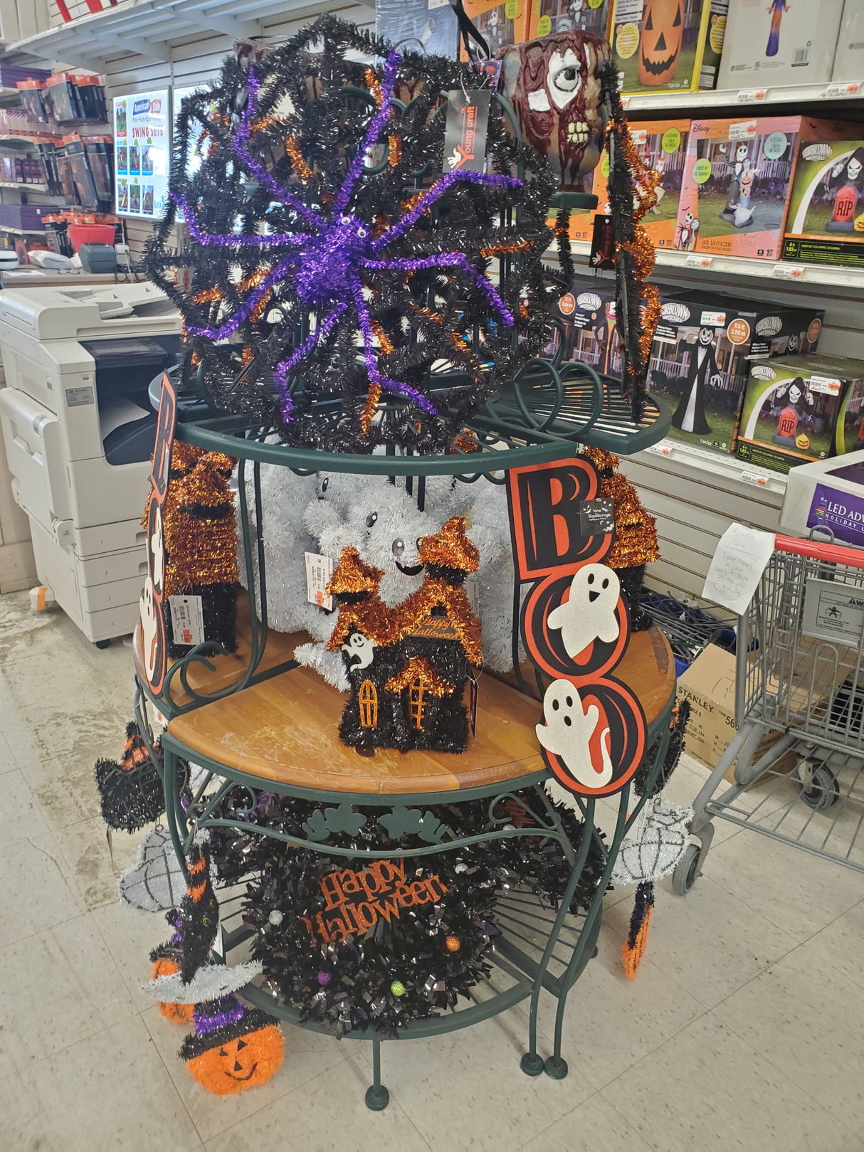 Halloween-themed decorations including a purple spider web, orange 'BOO!' sign, and black and orange wreaths in the Tinley Park Outlet store.