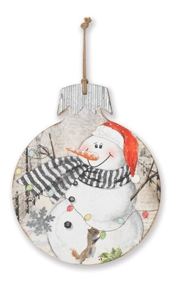 This wooden ornament features a snowman wearing a Santa hat smiling at a squirrel hanging from a string of lights.