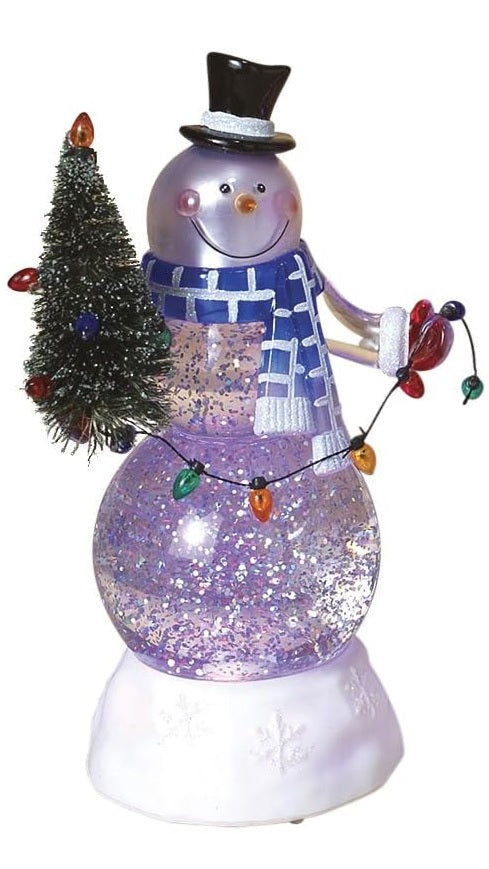 Glass snowman decoration. The snowman is wearing a black top hat, a blue and white scarf and red gloves. He's holding a small tree with a string of multi-colored lights. There's glitter inside.