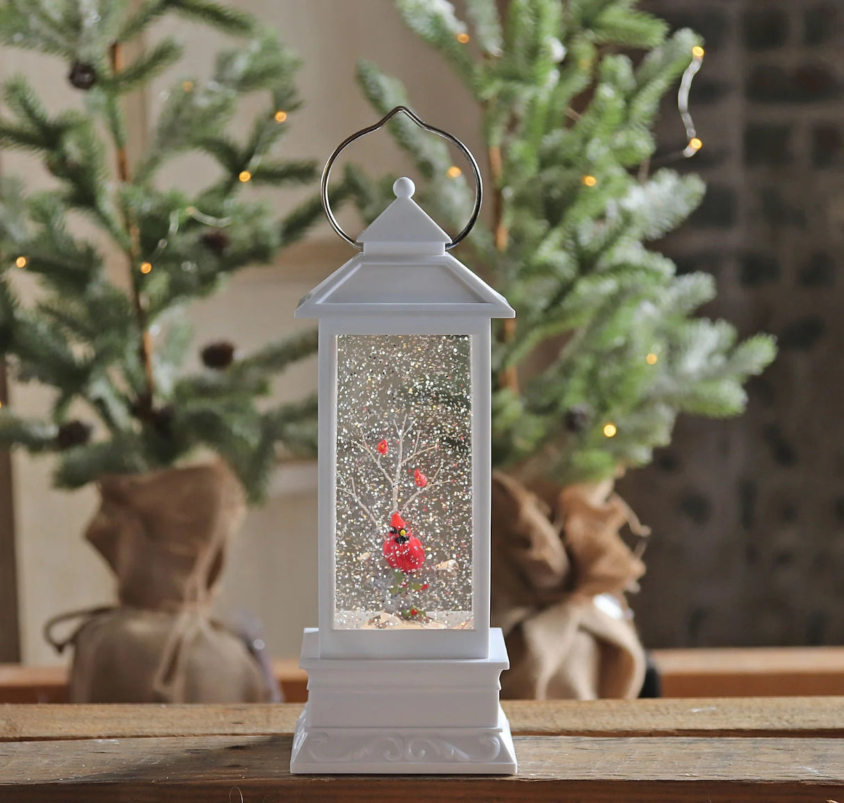 White lantern decoration with glitter and a woodland scene with a cardinal inside.