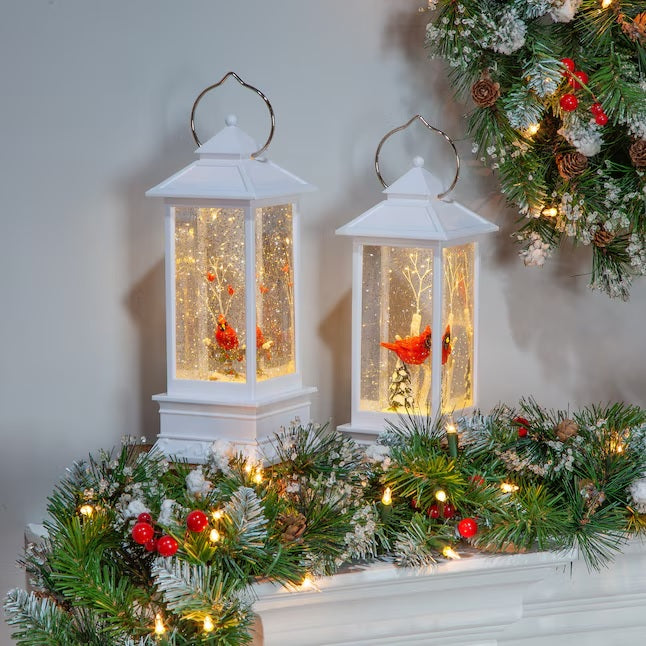 White lantern decoration with glitter and a woodland scene with a cardinal inside.