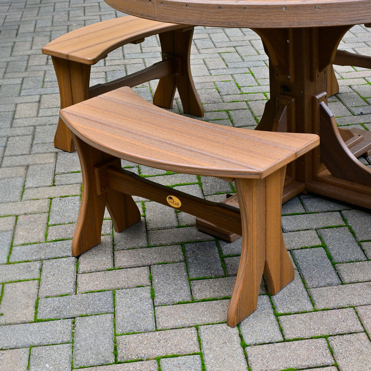 This is the Antique Mahogany colored Table Bench around a matching table on a stone patio.