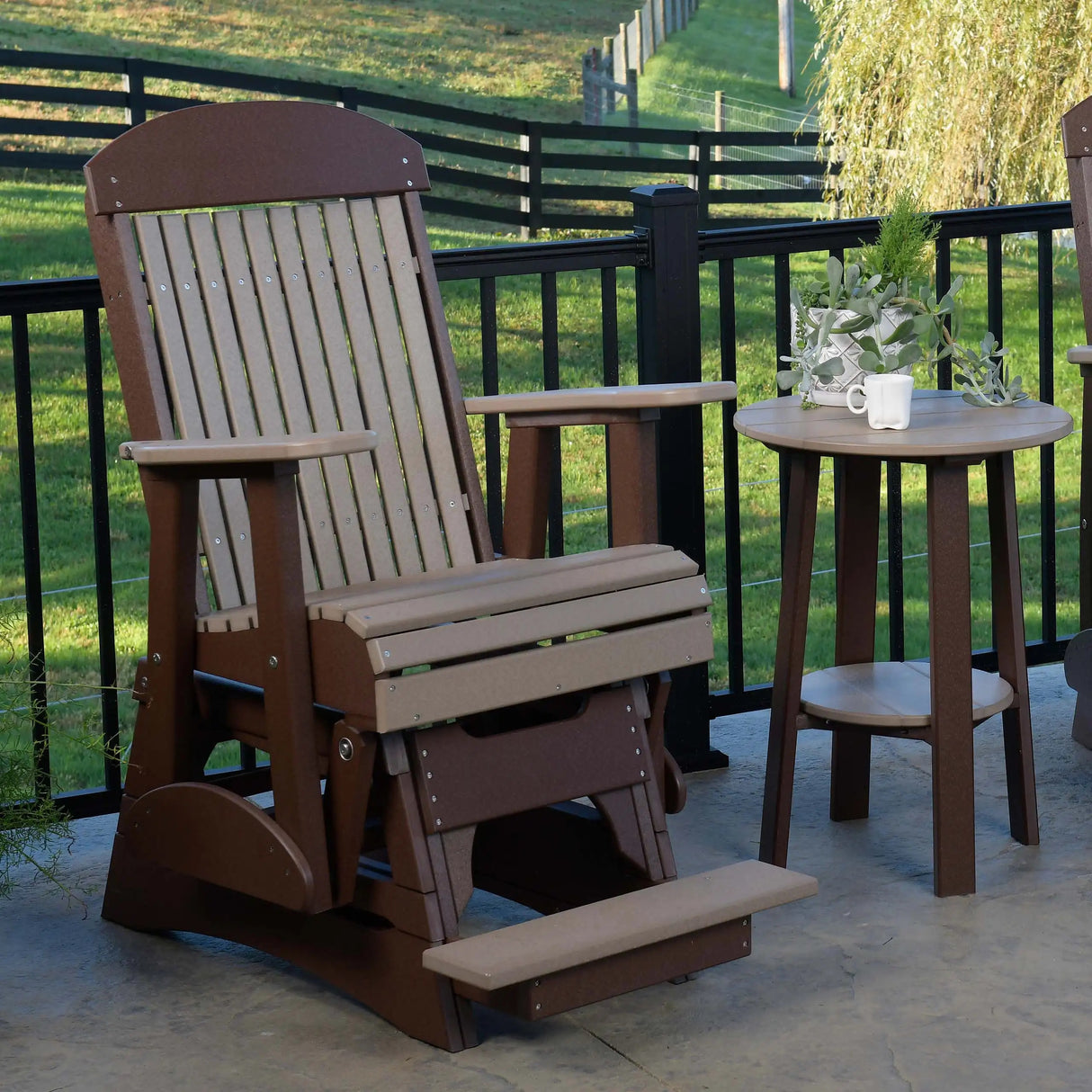 This is a lifestyle image showing the Weatherwood and Chestnut Brown colored balcony glider chair on a stone patio.