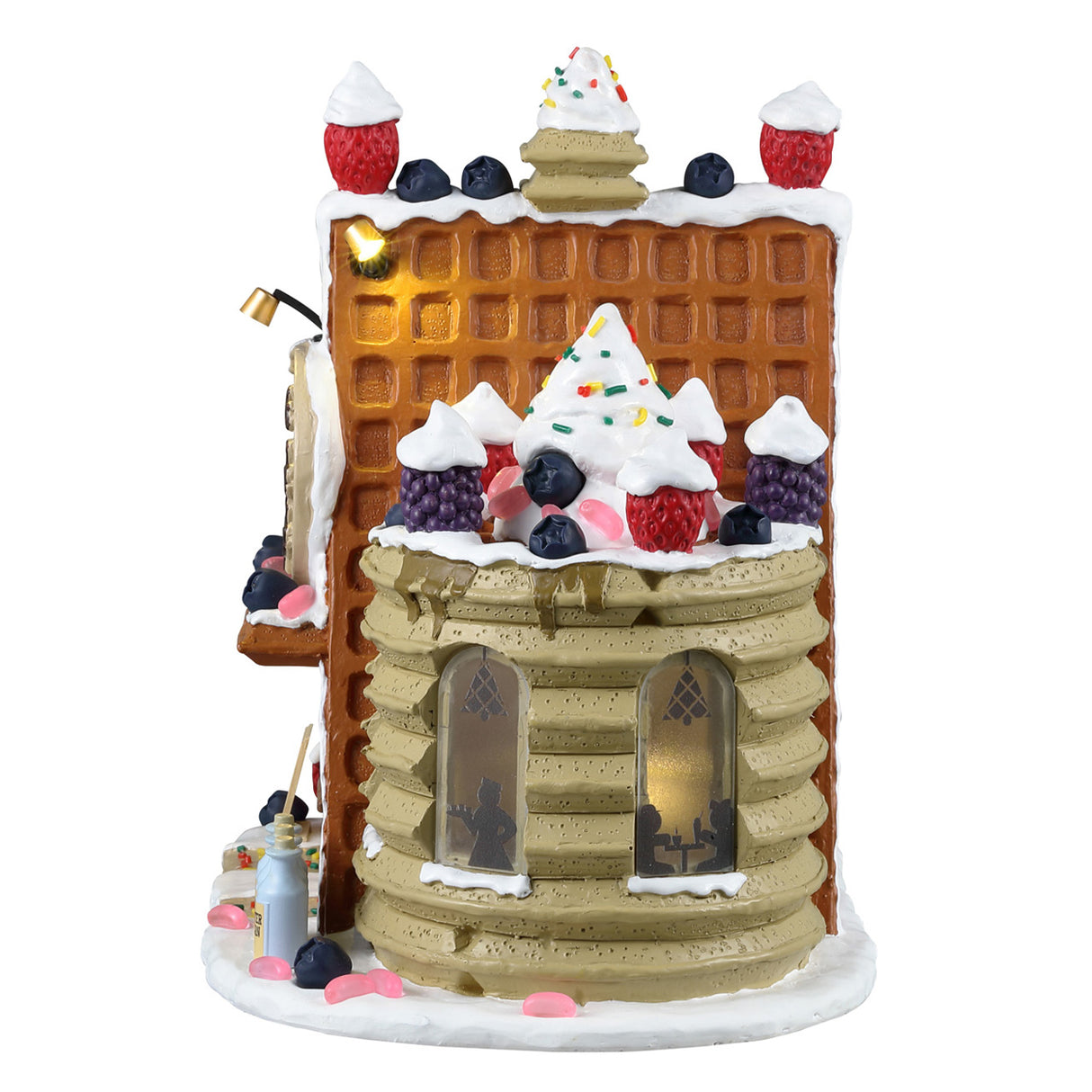 Resin lighted building for a Lemax Village display. Designed to look like a stack of pancakes and a roof made of waffles. The tops are decorated with whipped cream, sprinkles, raspberries, blackberries and pink jelly beans. The sign reads "Cookie's Waffle Cafe." There's a gingerbread person sitting behind the counter