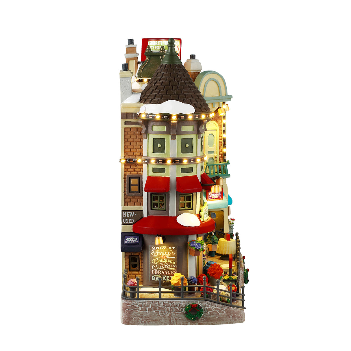 Resin building facade for a Lemax display. Designed to look like a bunch of store fronts. Signs read: "Fay's Flowers & Bouquets," "The Burger Cafe," "Jolly Toys & Games," "Quilter's Island," Sweet Spot" and "Hot Fresh Coffee at the Christmas Bazaar!" There are flowers everywhere and a billboard on the roof advertising a visit with Santa.