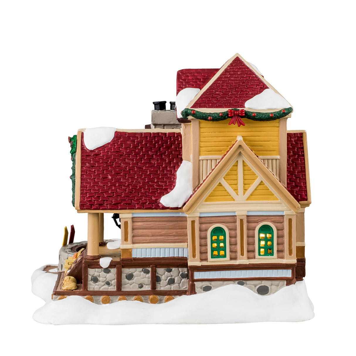 Porcelain lighted building for a Lemax display. Designed to look like a wooden cottage with a stone chimney and a stone hot tub on the porch. There's snow on the building and features wreaths and garland accents. There's a balcony with a chair and a table. There are coats hanging on the side and a few pairs of boots. There's a dog sleeping on the porch and a few pairs of skis leaning up against the stone hot tub.