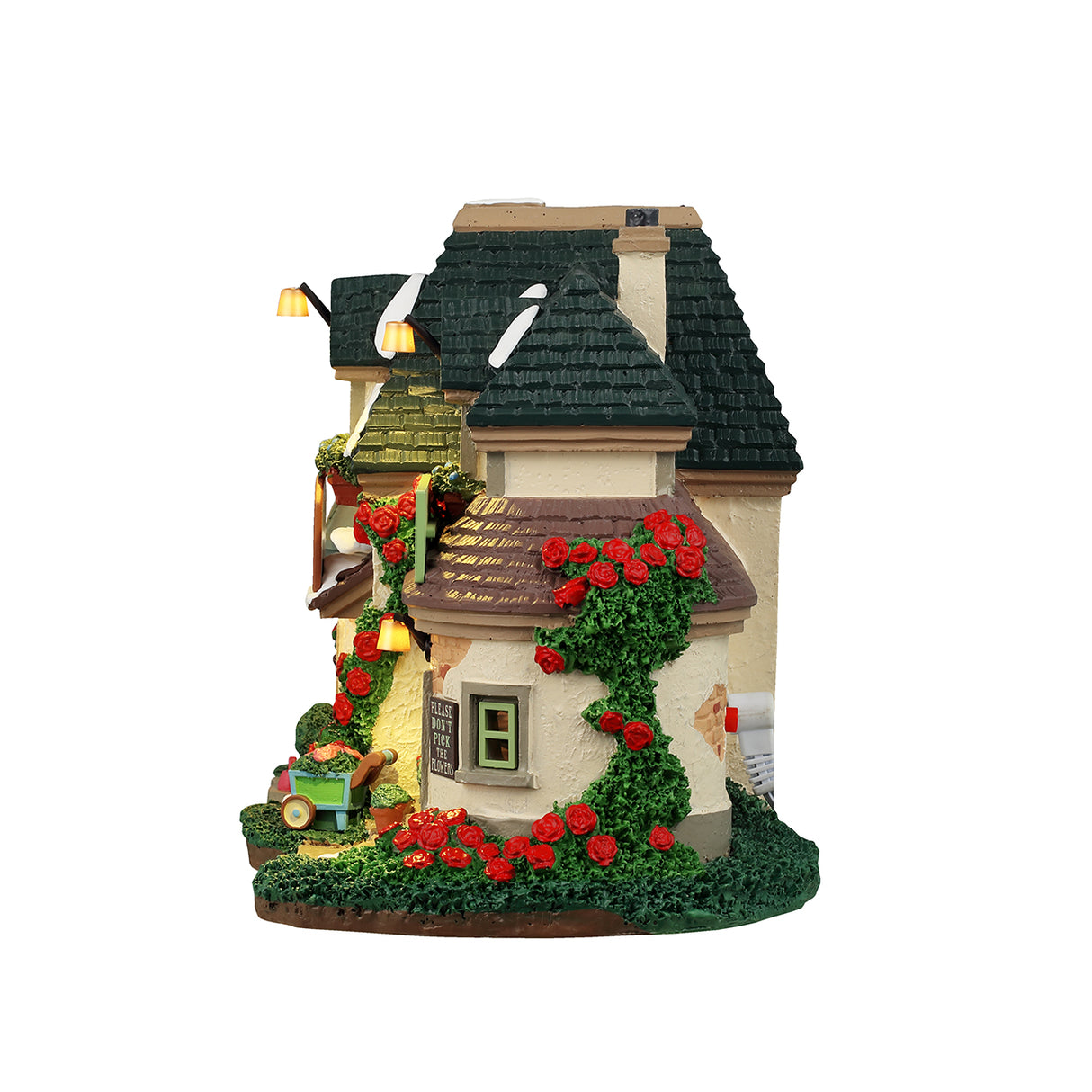 Resin lighted building for a Lemax display. Designed to look like a charming cottage covered in moss and flowers. There's a bright red door with a decorated wreath on it. There are signs that read "Farnley Moor Cottage," "Flowers" and "Please don't pick the flowers." There's snow on the roof.