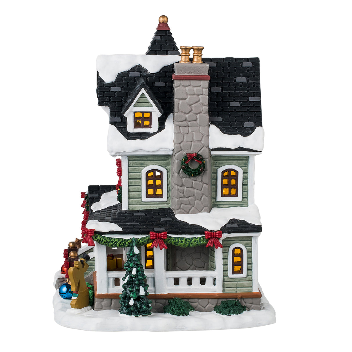 Porcelain lighted building for a Lemax display. Designed to look like a Victorian-era house covered in snow. It's decorated with decorated wreaths, garland, large shiny ornaments on the ground, Christmas trees and bushes and an angel silhouette.