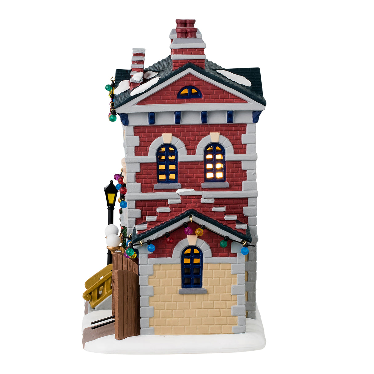 Porcelain lighted building for a Lemax display. Designed to look like a red, yellow and gray brick police precinct office. The roof and sidewalk has snow on it. There are multi-colored lights hanging from the roof. The windows have wreaths and there's a car coming out of the side garage.