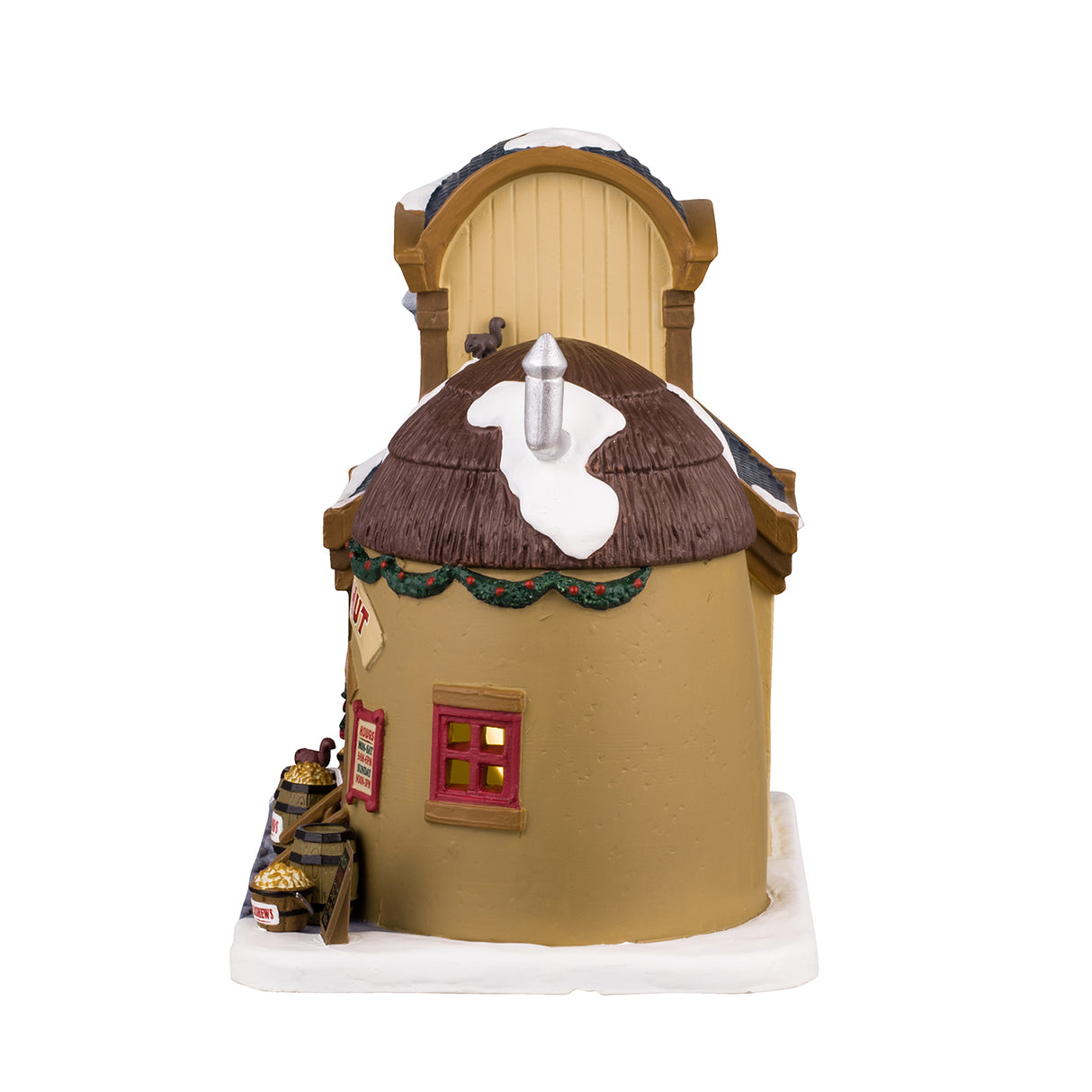 Porcelain lighted building for a Lemax Village display. Designed to look like a store booth connected to a building that is shaped like a coconut. There's snow on the roof and the sidewalk. There's a man behind the booth wearing an apron. On the upper level of the building, there's a Nut Butter Loft. There's a decorated wreath and garland near the front door. There are barrels of different nuts and a few squirrels.