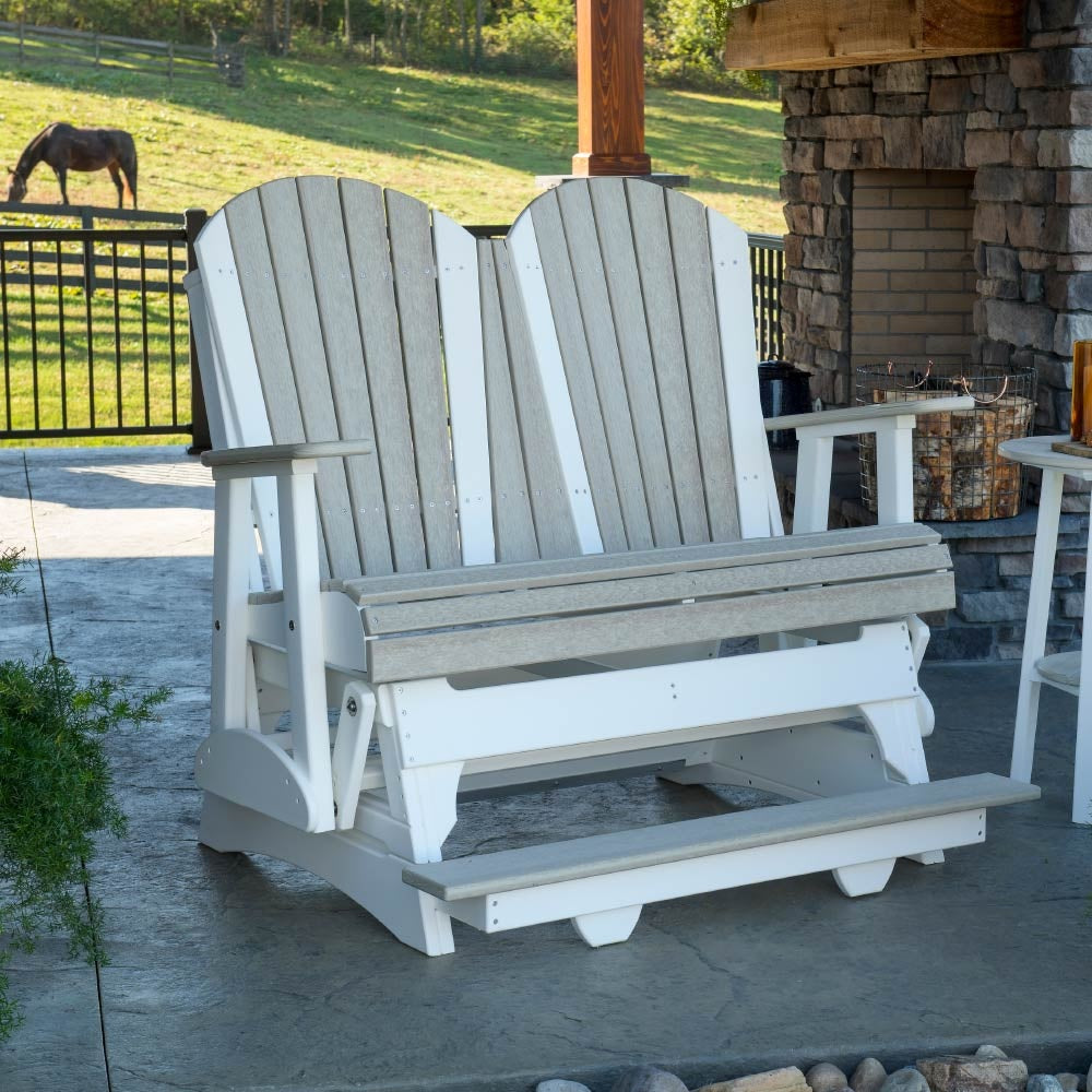 This is a Birch and White Adirondack balcony glider on a stone patio with a horse in the background.