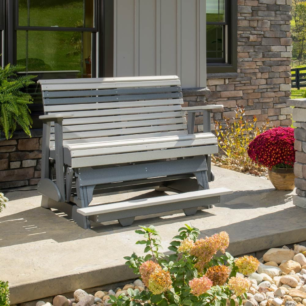 This is a lifestyle image showing the Dove Gray and Slate colored glider bench in front of a house.