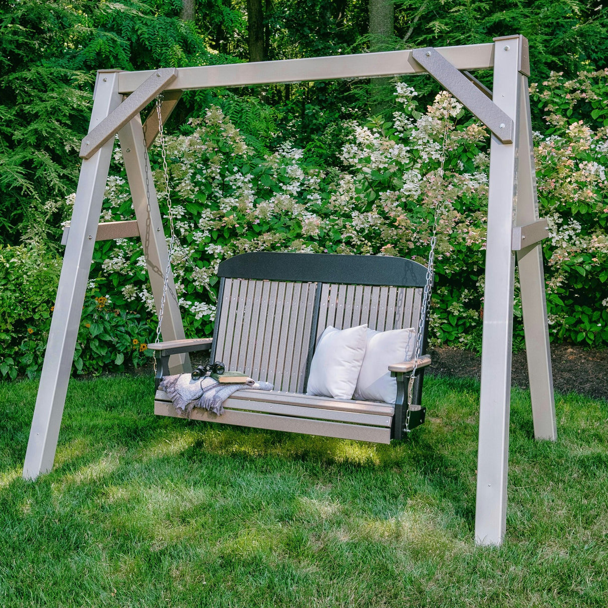 This is a lifestyle image showing the Weatherwood and Black colored swing in a grassy backyard.