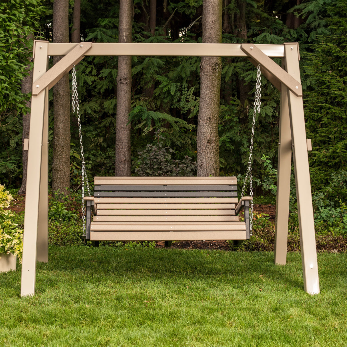 This is a lifestyle image showing the Antique Mahogany and Black colored porch swing in a grassy backyard.