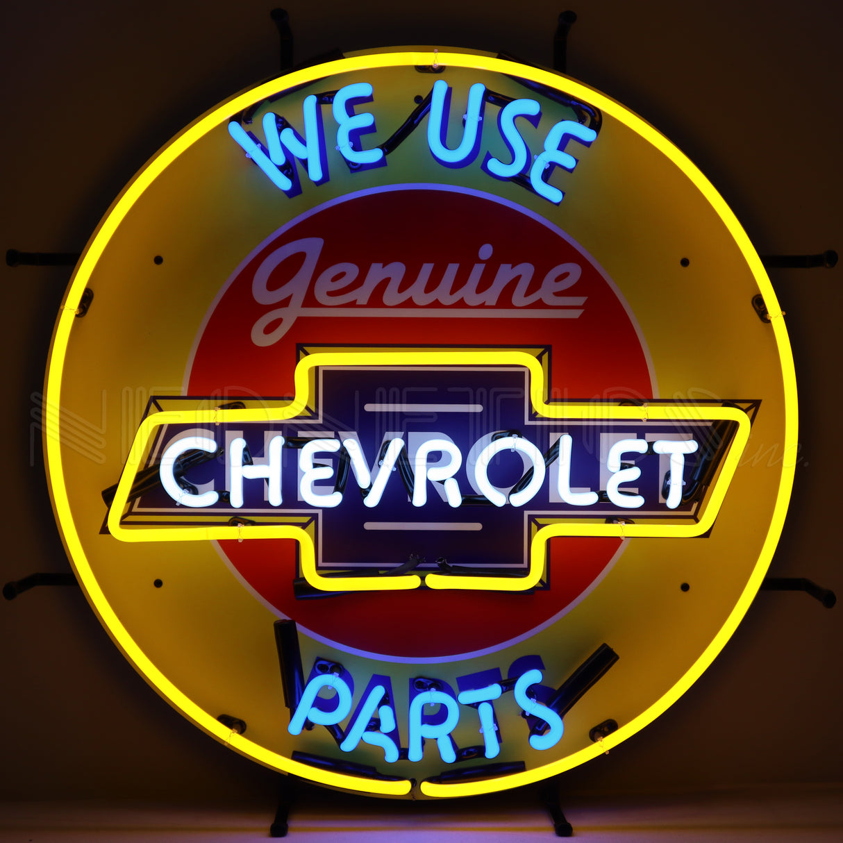 This particular image shows this neon sign in the dark. Circular neon sign that reads "We use genuine Chevrolet parts." The background is yellow and the texts are all different colors: Light blue, red, white and dark blue.