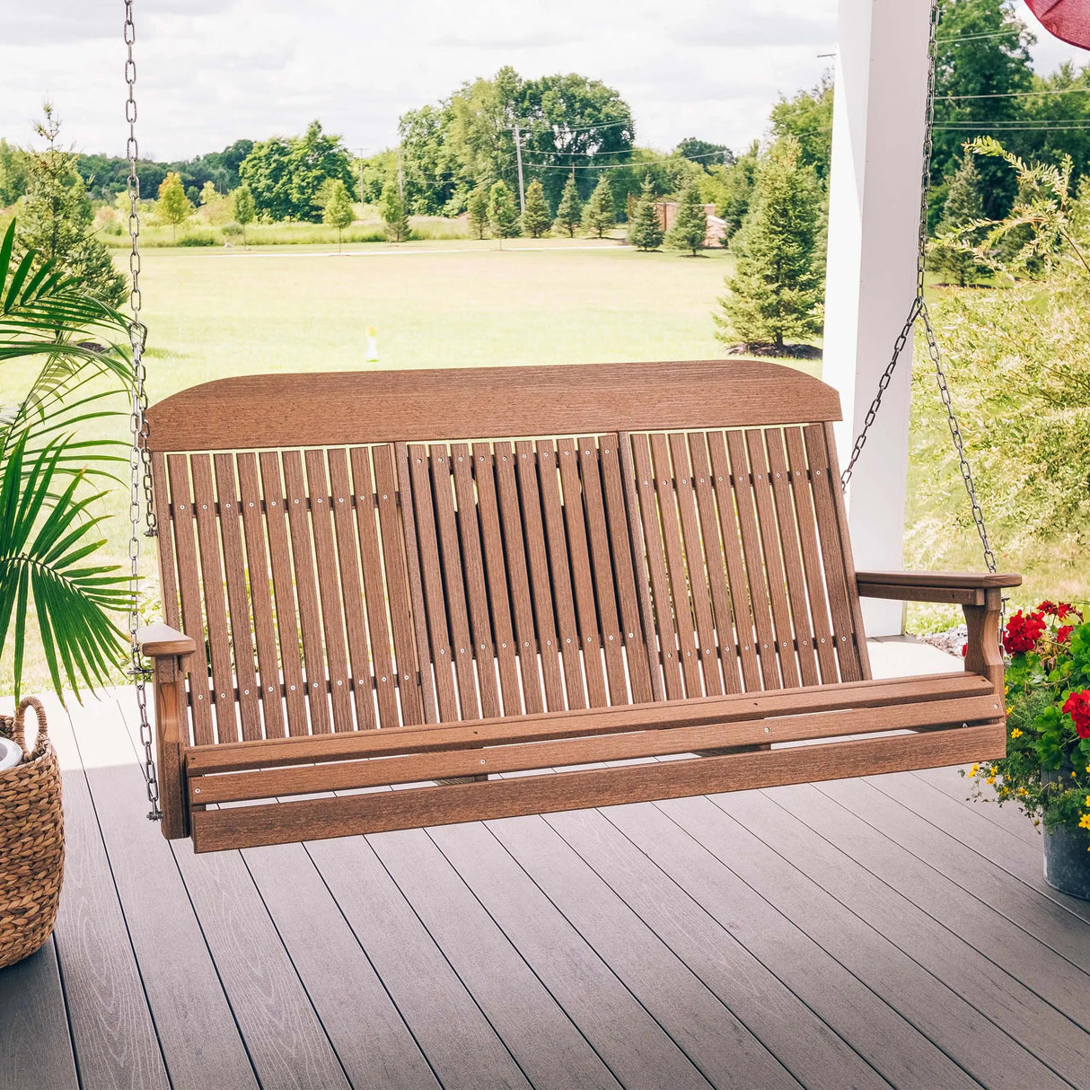 This is a lifestyle image showing the Antique Mahogany porch swing on a wooden porch. The center console is up so you can see three people.