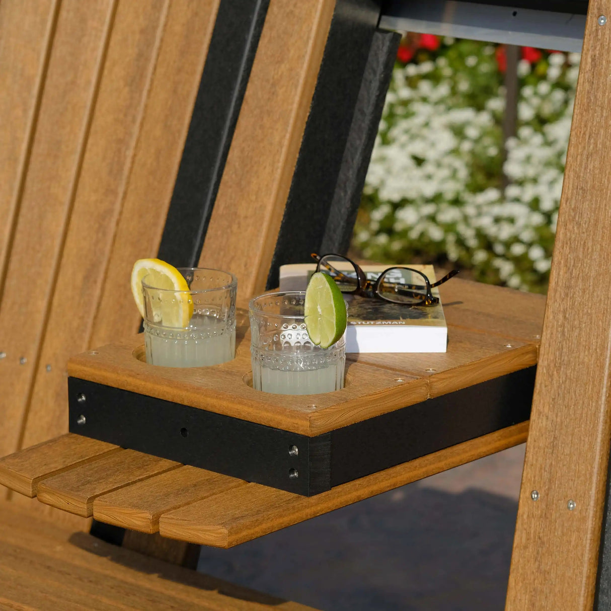 This is an up close view of the center console of the bench being down. It's being used as a table, holding a book and a pair of glasses. There are also two glasses of lemonade in the cupholders.