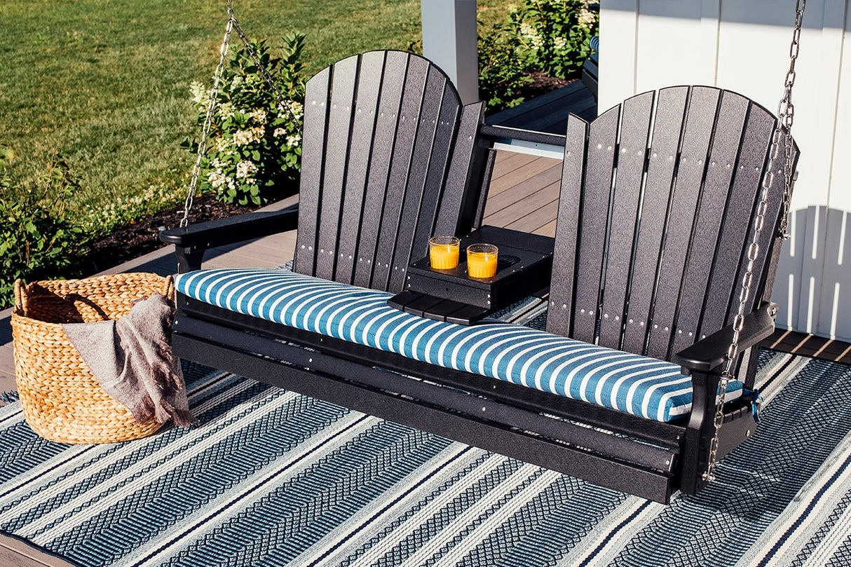 This is a lifestyle image showing the Black Adirondack swing on a patio that's covered with a blue and white rug. The center console is down and there are two cups of orange juice in the cupholders.