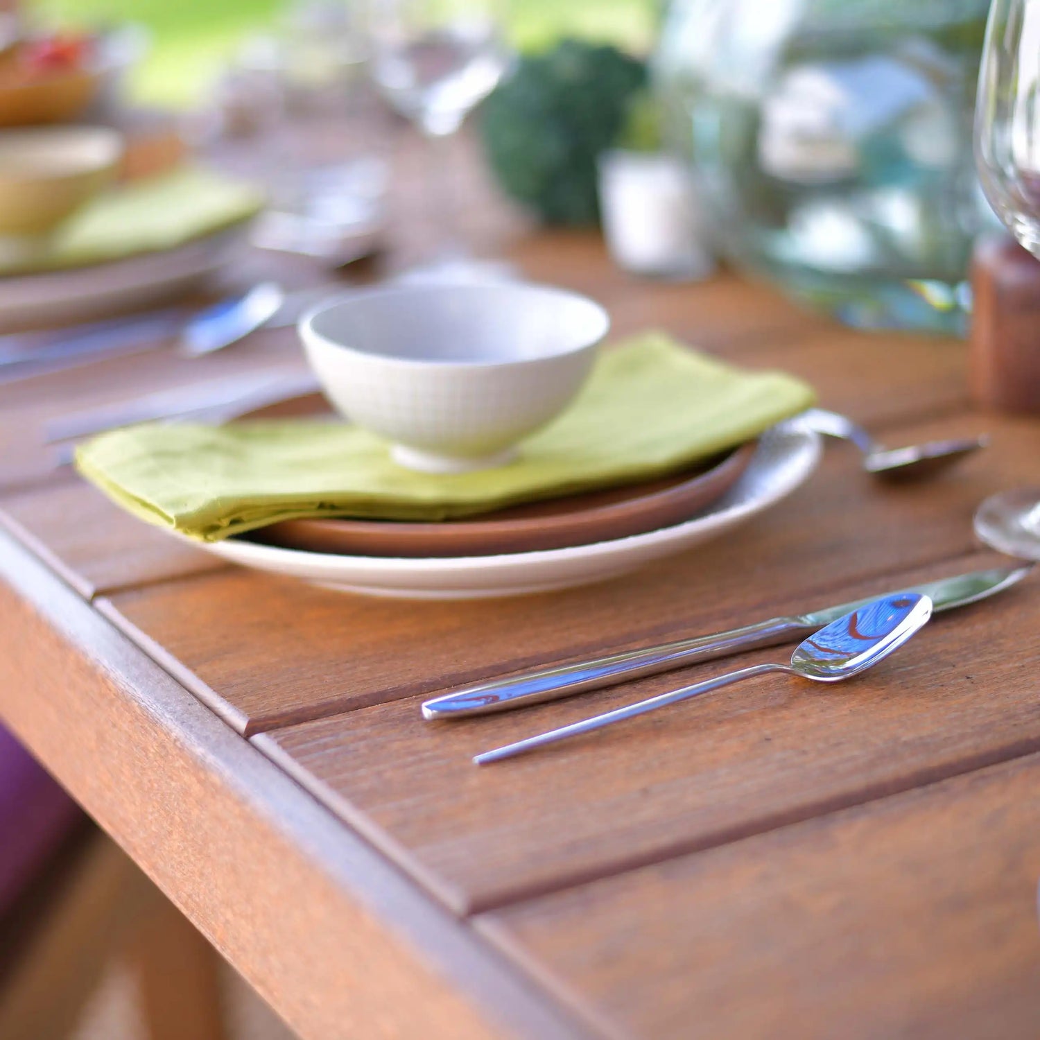 This is an up close view of the Chestnut Brown colored table There are plates and silverware on it.