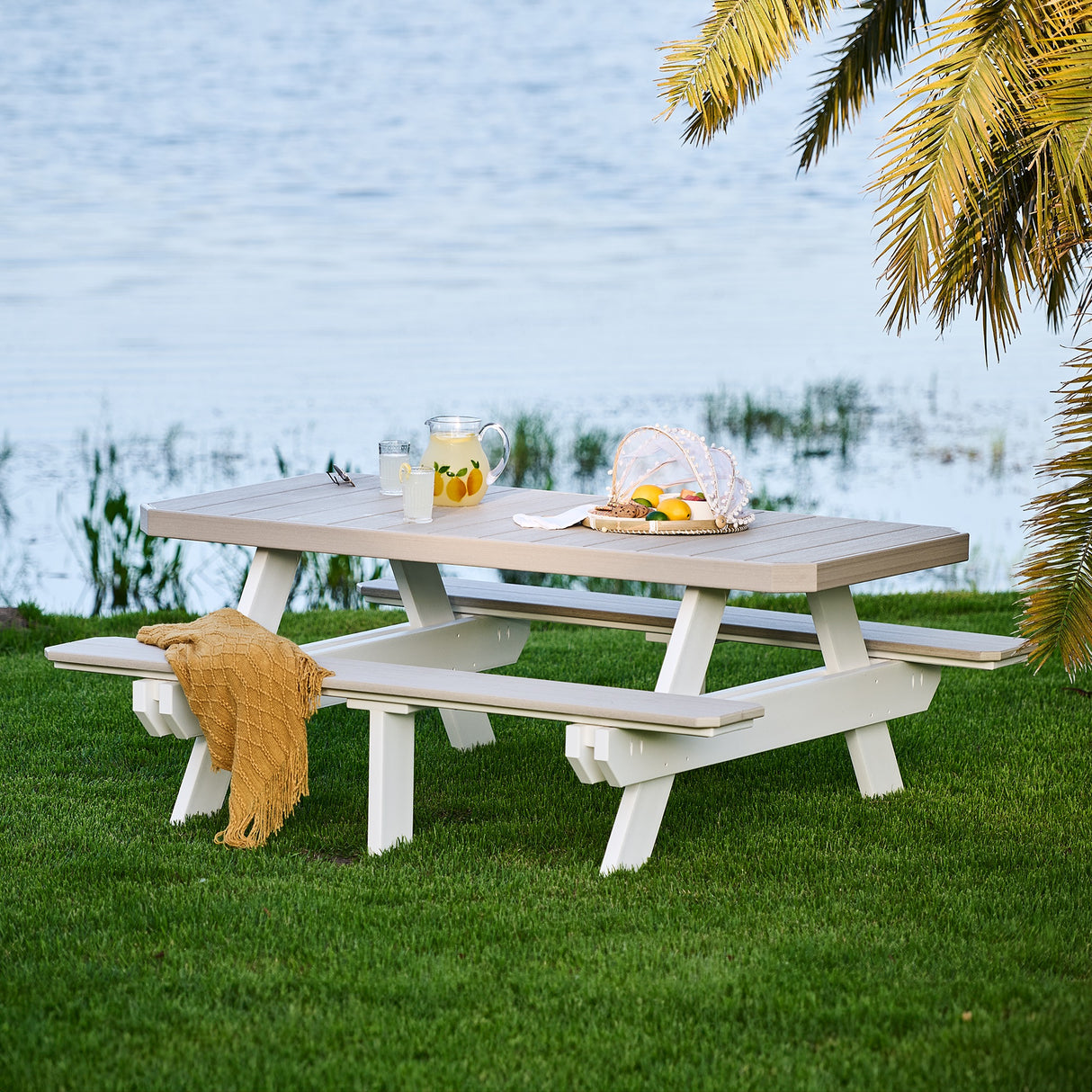 This is the Birch and White colored picnic table with attached benches. It's in the grass next to a pond.