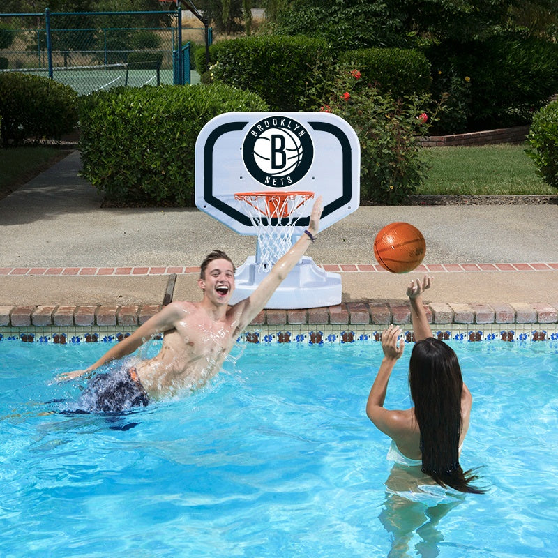 This is a lifestyle image showing two people playing basketball in the pool, aiming the ball for the Brooklyn Nets themed basketball hoop.