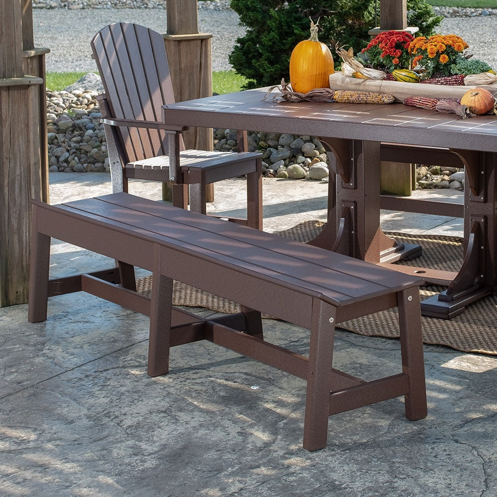 This is a lifestyle image showing the Chestnut Brown colored dining bench in front of a matching table on a stone patio.