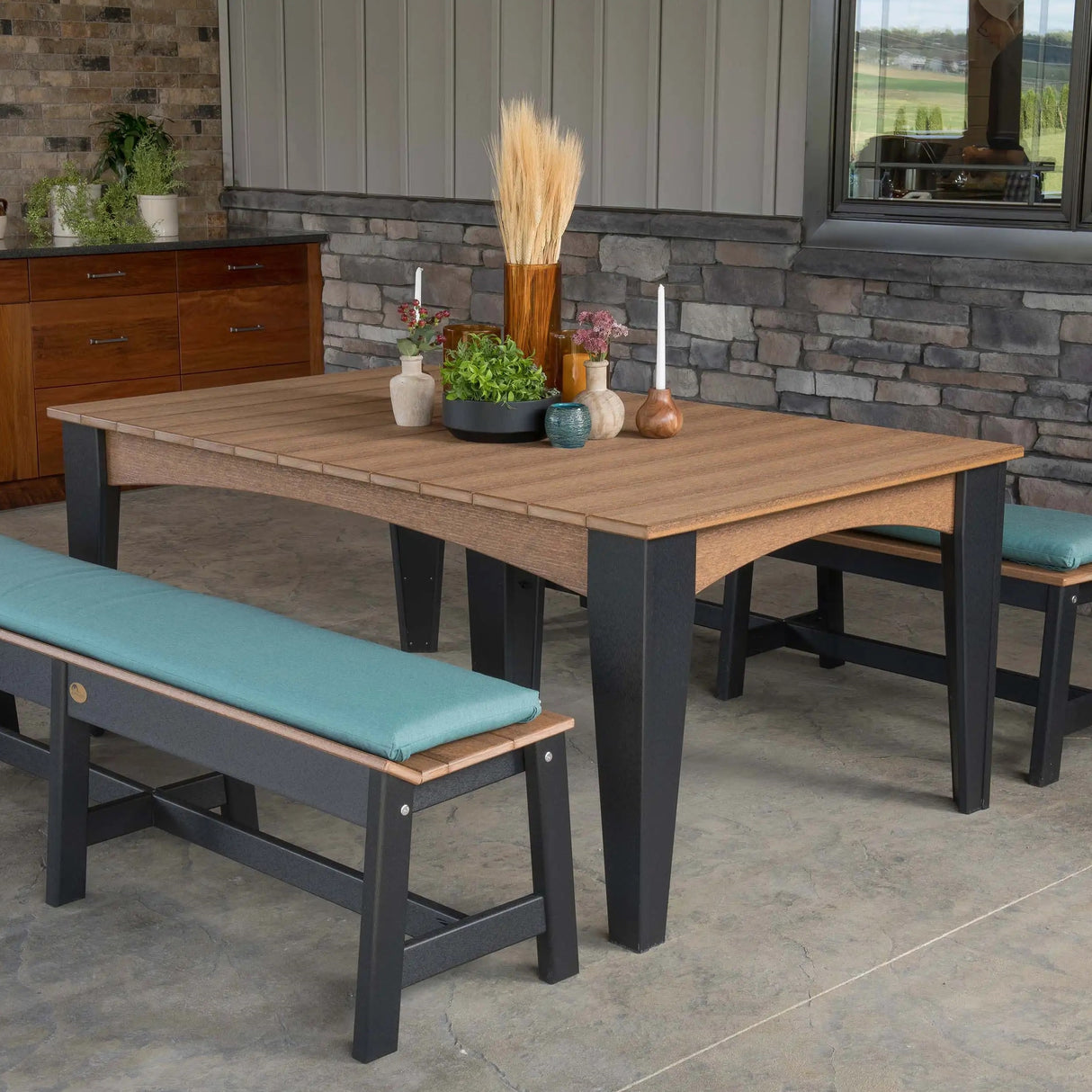 This is a lifestyle image showing the Antique Mahogany and Black colored dining table with matching benches. The benches have teal colored seat cushions on them.