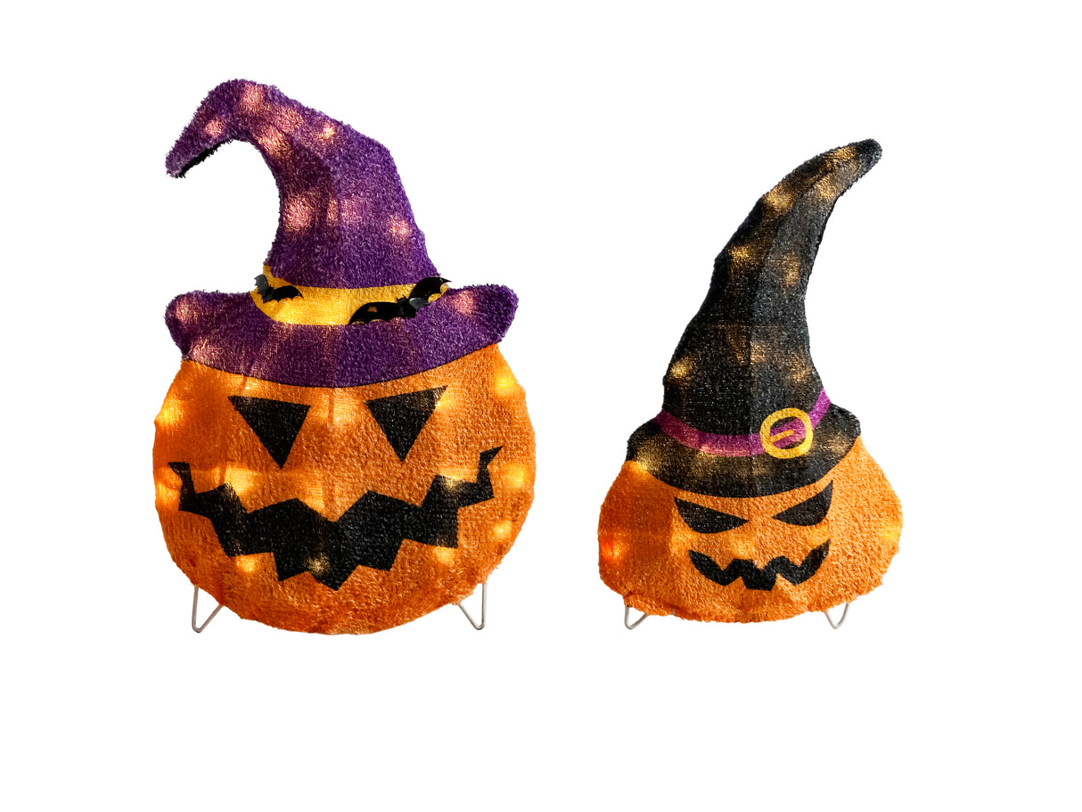This image shows the two decorative pumpkin sculptures on a white background. The pumpkin on the left is slightly larger than the pumpkin on the right. The pumpkin on the left is wearing a purple and yellow witch hat with two small black bats on it. The pumpkin on the right is wearing a black and purple witch hat with a yellow buckle.