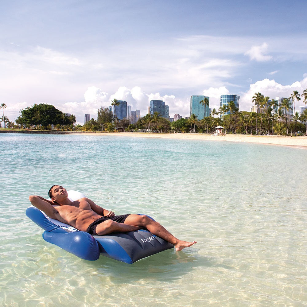 This is a lifestyle image showing a man resting on this inflatable lounge in the middle of the ocean.