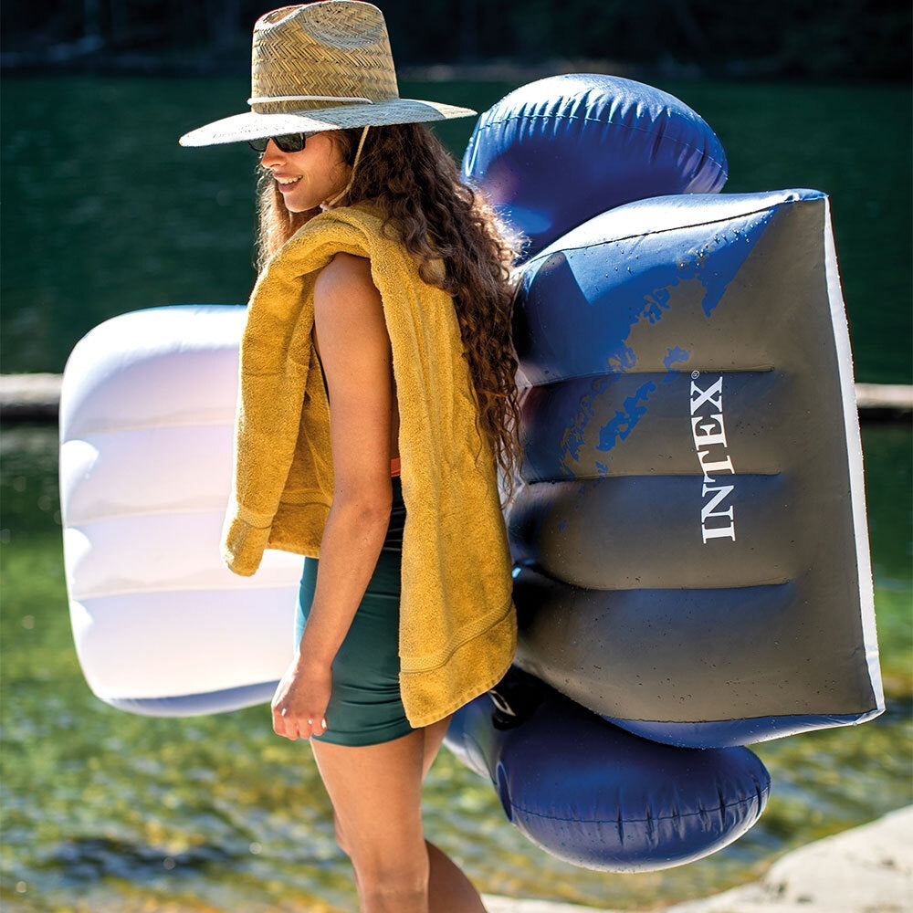 This is a lifestyle image showing a woman wearing a hat and a towel bringing this inflatable chair to the lake.