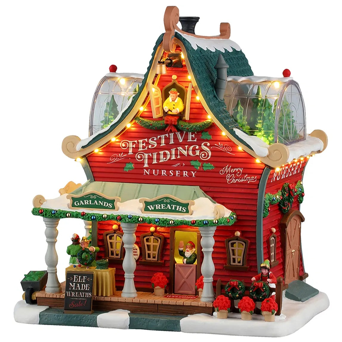 This image shows what this Lemax Santa's Wonderland lighted building looks like on a white background. It was designed to look like a red house turned into the Festive Tidings Nursery. On the porch, there's a table with elf made wreaths for sale. On the side of the house, there's an elf decorating wreaths. There are two dome windows on the roof where you can see some trees inside.