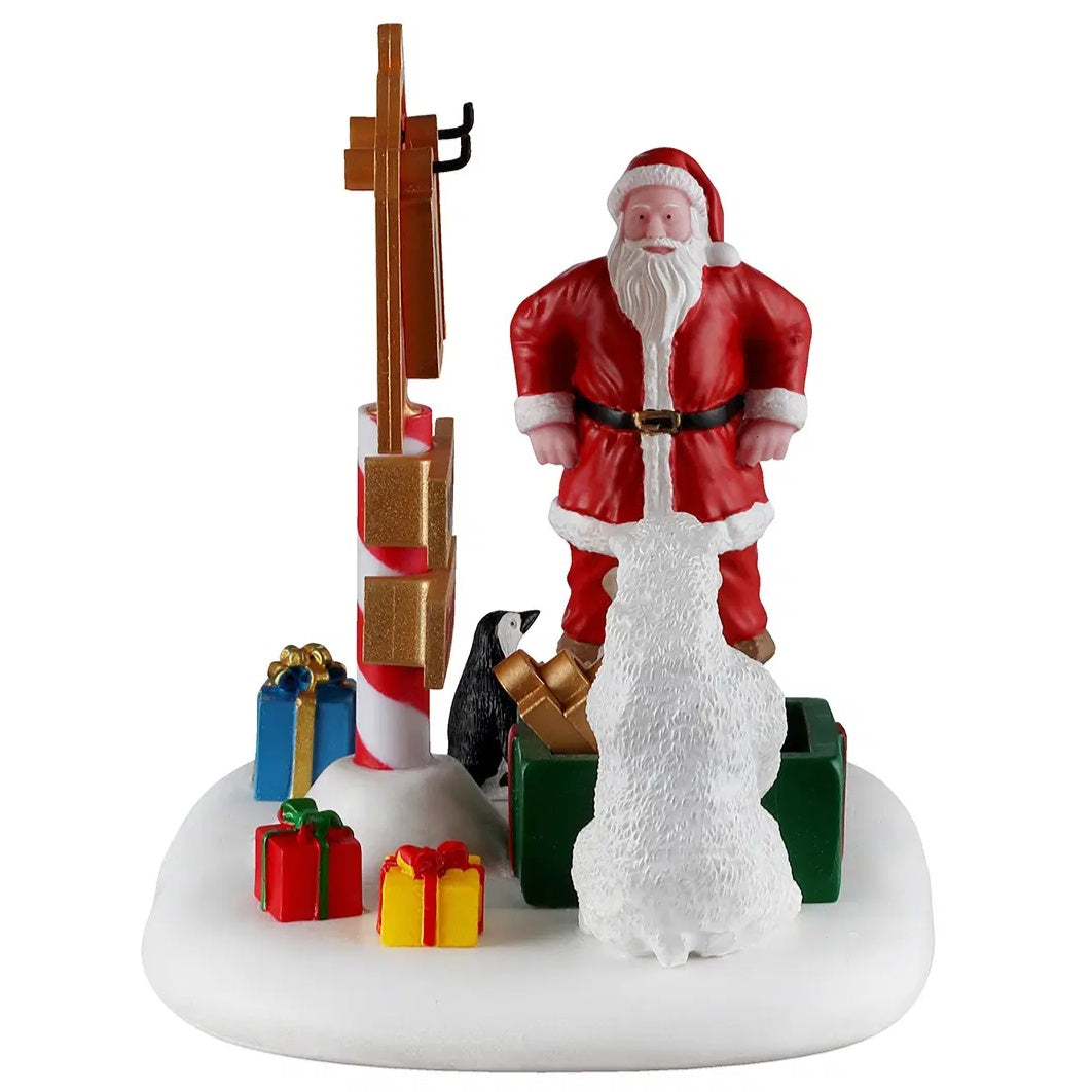This image shows a side of this table accent. Santa is standing with his hands on his hips while the penguin stands next to him among different colored present boxes.