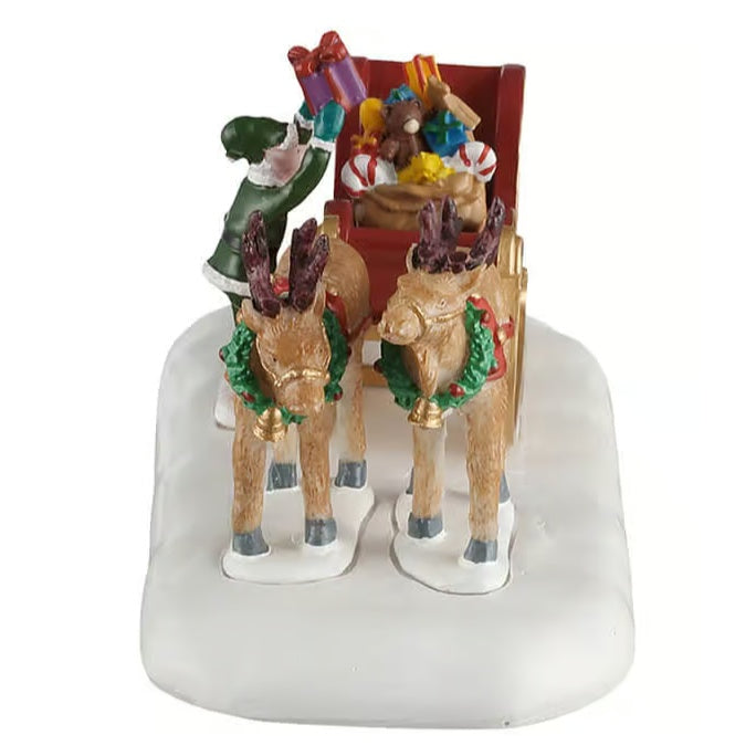 This image shows what this table piece looks like from the front. The reindeer are wearing wreaths with gold bells on them. The reindeer, elf and sleigh are all in the snow.