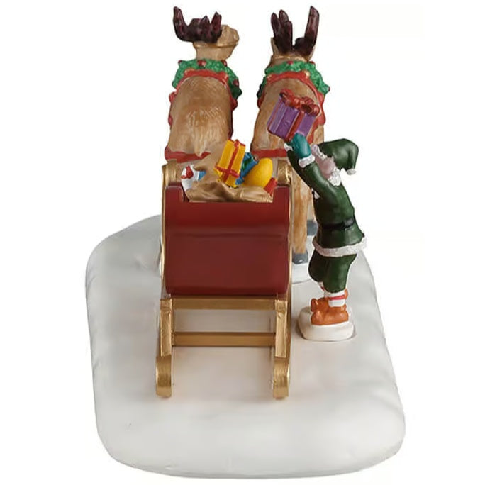 This image shows what the table piece looks like from the back. The sled is full of presents and there's an elf on the right side loading more presents into it. The two reindeer are wearing wreaths around their necks.