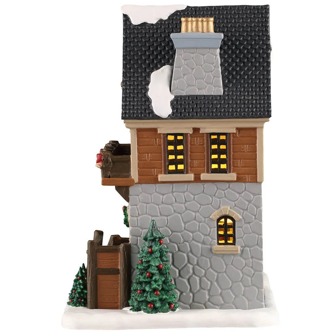 This image shows what the side of this building looks like. There are two windows on the second floor and one window on the first floor. The wall is half siding and half stones.