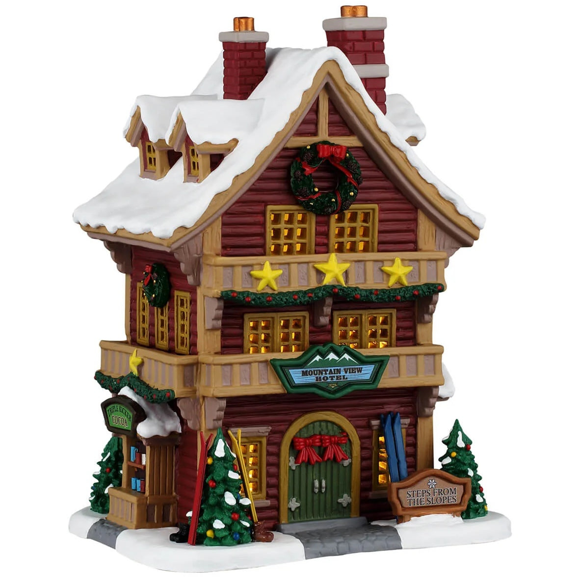 This image shows what this Lemax building looks like on a white background. It was designed to look like a tall log cabin-themed hotel. There's snow on the roof and the sidewalk. There are three gold stars above the front door. The front doors are decorated with red bows. There are trees on either side of the front door and skis leaning against the wall.