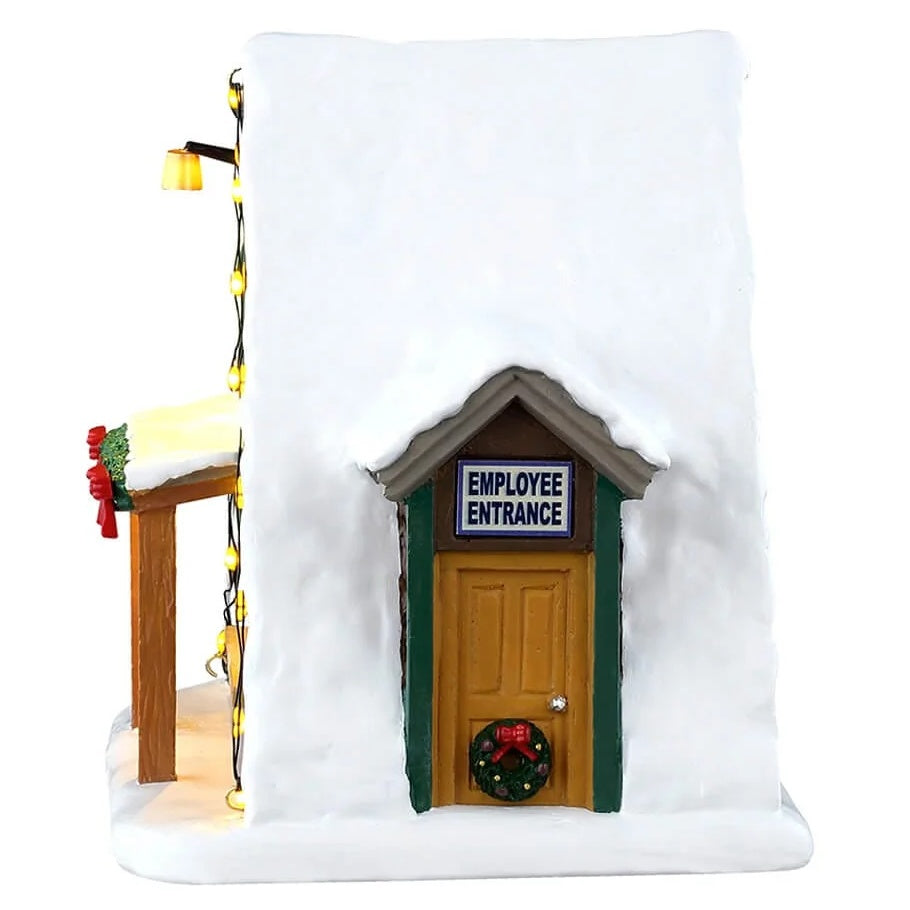 This image shows what the side of this building looks like. There's a wooden door with green trim that reads "EMPLOYEE ENTRANCE." There's a decorated wreath on the door.