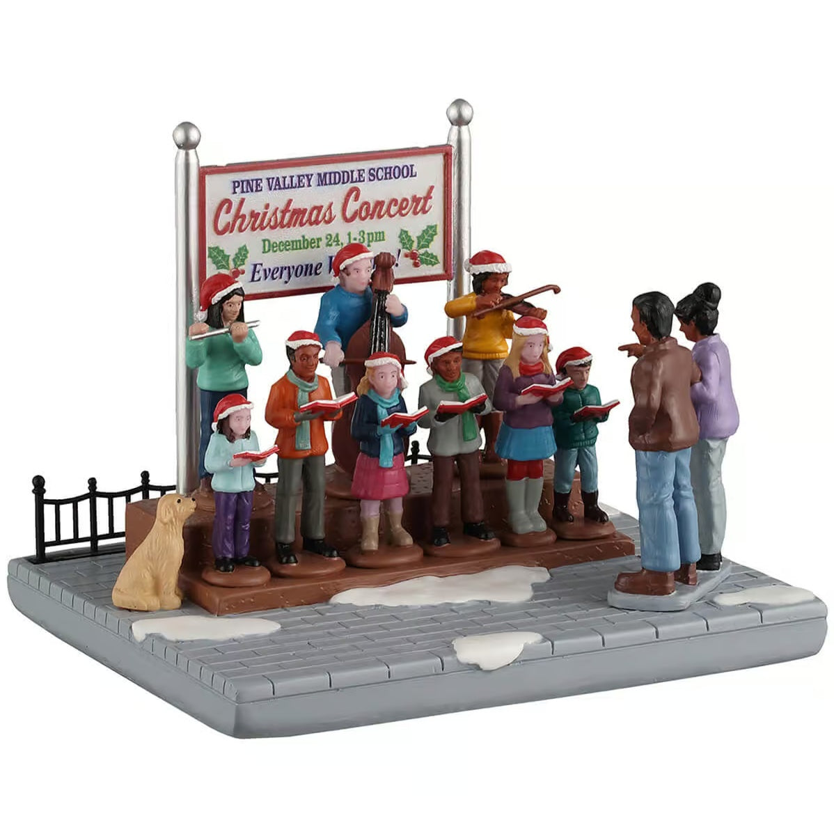 This image shows what this table piece from Lemax looks like on a white background. It was designed to look like a a group of people singing songs on a snow-covered stone sidewalk. There's a sign behind them that reads "Pine Valley Middle School Christmas Concert. December 24, 1-3pm. Everyone welcome!"