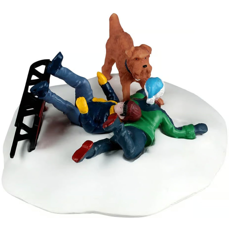 This image shows what this table accent looks like from the side. One of the boys landed on his stomach and he's wearing a blue hat, a green jacket, a blue scarf, blue gloves, blue pants and blue boots. The other boy landed on his back and is wearing a maroon hat, a blue jacket, a yellow scarf, yellow gloves, blue pants and blue boots. The dog is an orange-ish brown color and is wearing a black collar.