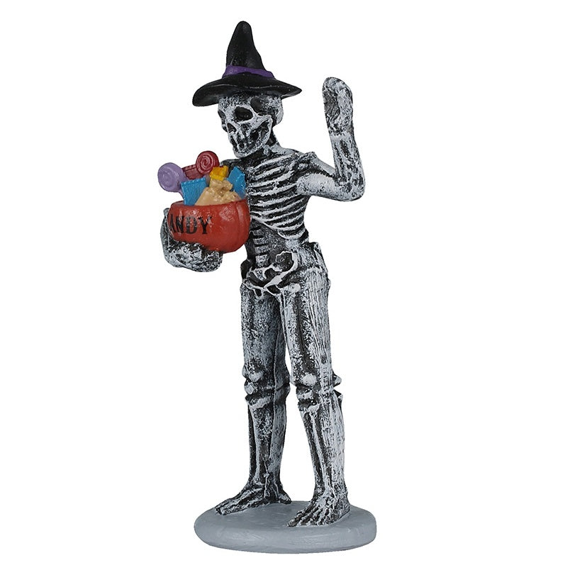 This image shows one of the figurines that was designed to look like a skeleton wearing a black witch's hat and he's holding an orange pumpkin basket filled with multi-colored candy.