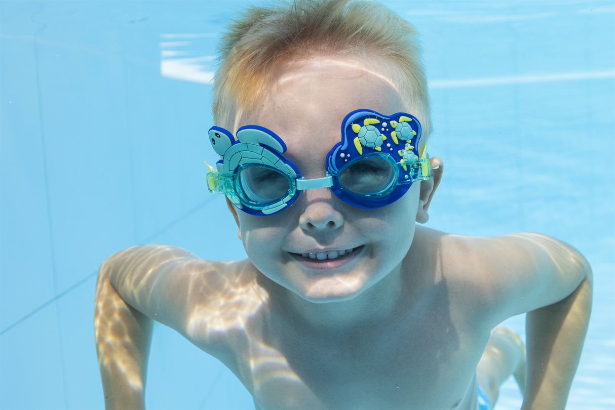 This is a lifestyle image showing a young boy underwater wearing the turtle themed kids goggles.